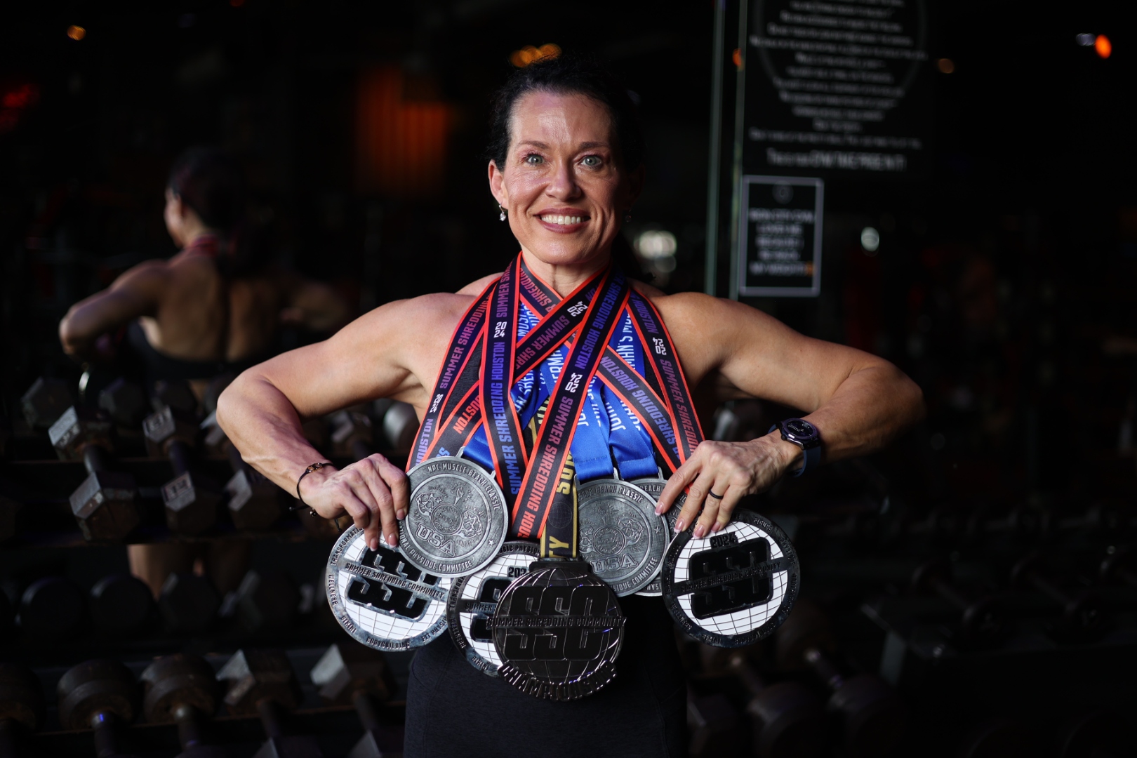 Jamie wearing five competition medals, the bodybuilding promise, delivered